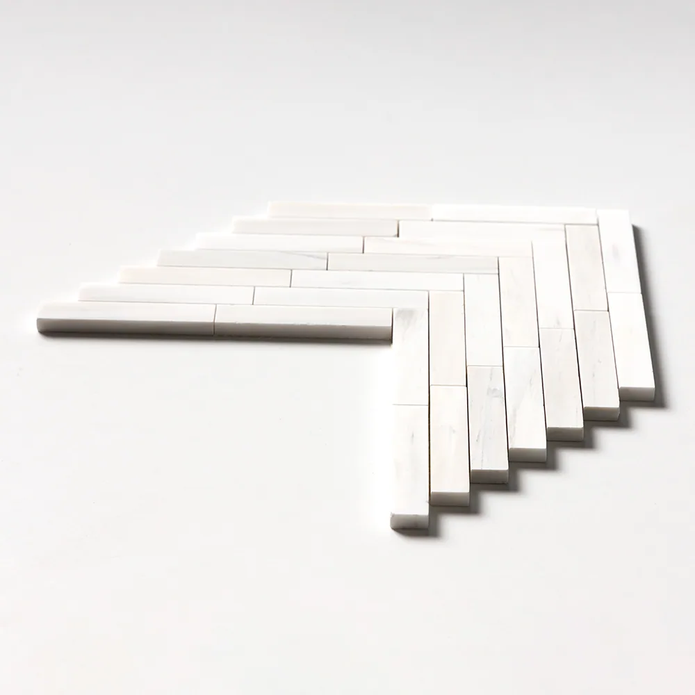 Large herringbone mosaic of long, narrow pure-white marble batons, photographed at a low angle so the stepped edge of the sheet is visible.