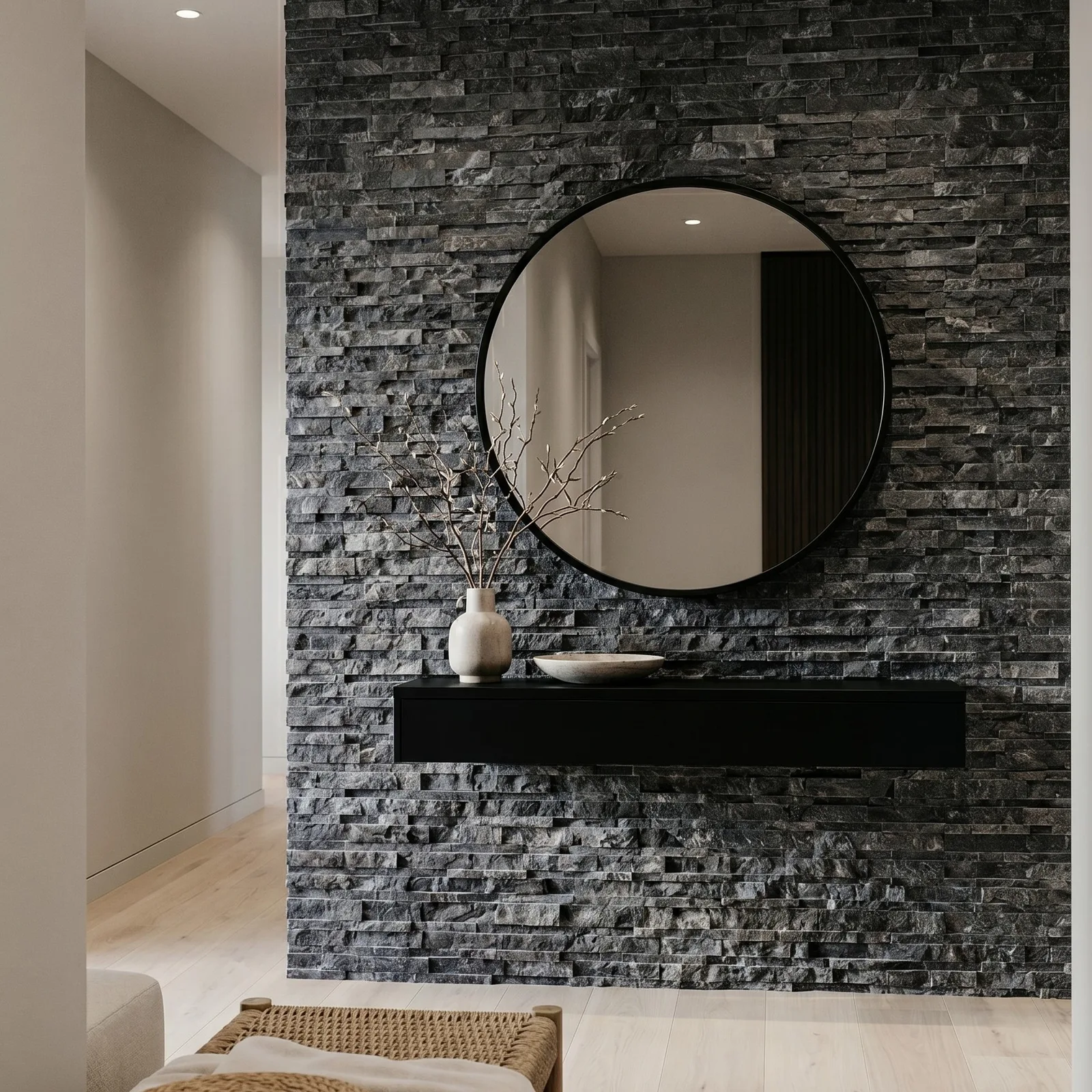 Bathroom wall in black marble ledger panel with a round black-framed mirror and a dark floating vanity set against the charcoal stone.