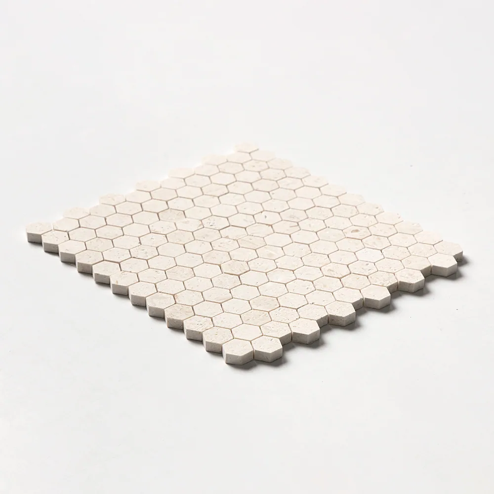Small one-inch limestone hexagons in pale sand, the sheet tilted low so the honeycomb edge steps away across a white ground.