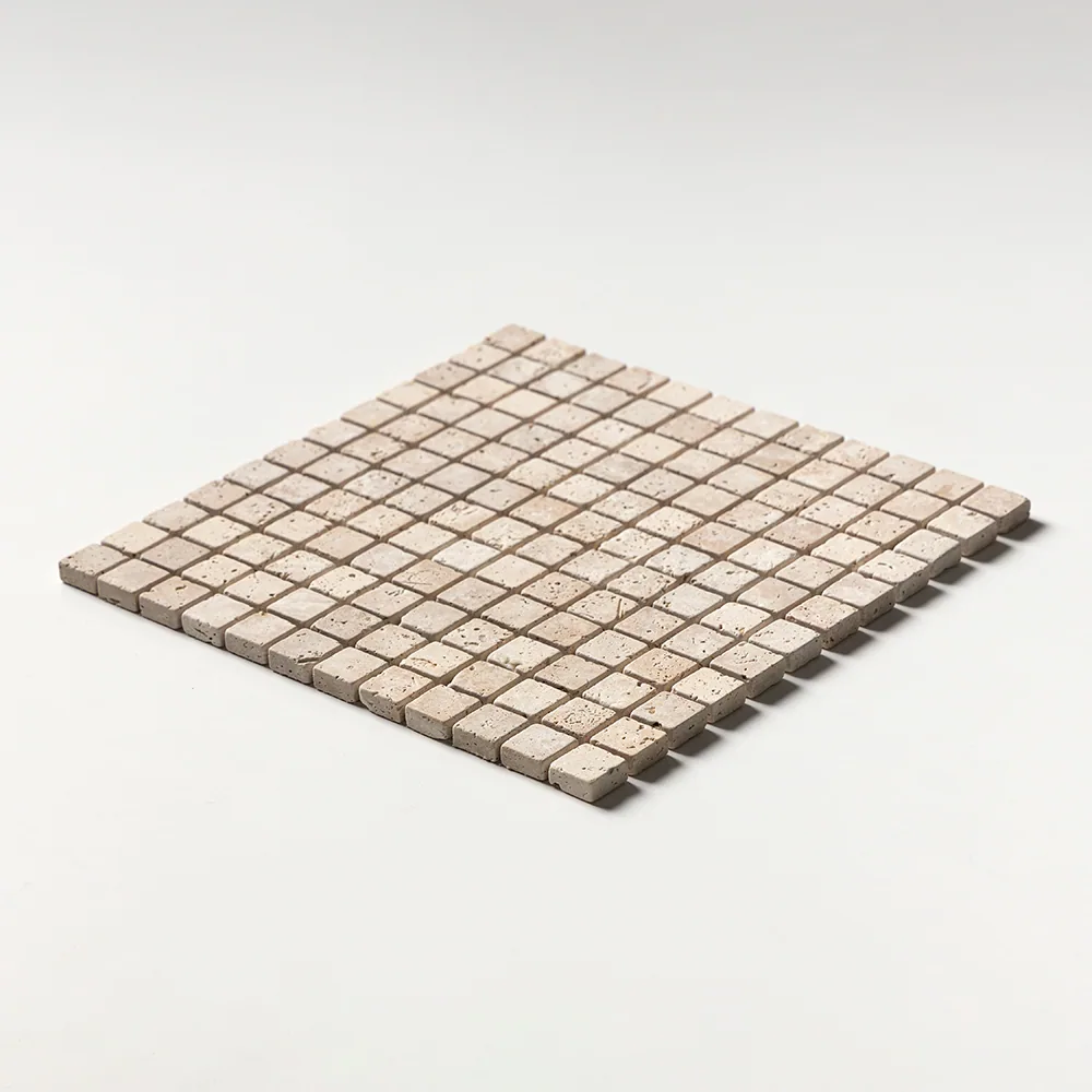 Ivory travertine mosaic of one-inch tumbled squares in warm cream, the sheet seen at a shallow angle on white.