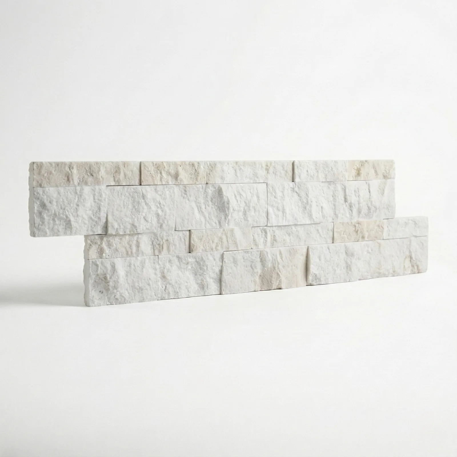Two courses of limestone ledger panel on a pale studio ground, the split faces cream and chalk white.