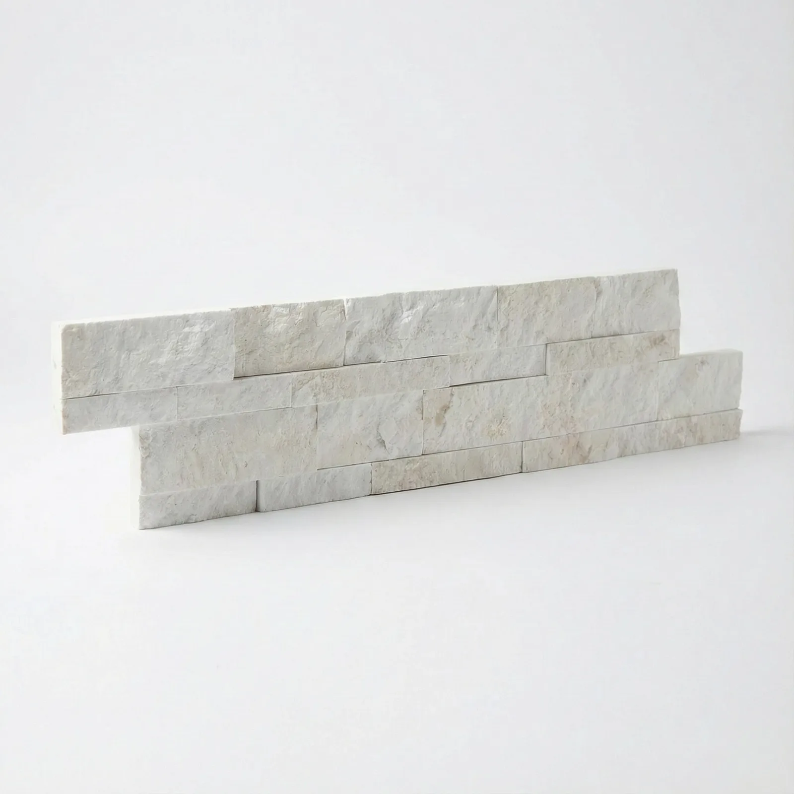 Two courses of Myra Beige marble ledger panel on a pale studio ground, warm cream and biscuit tones across the split faces.