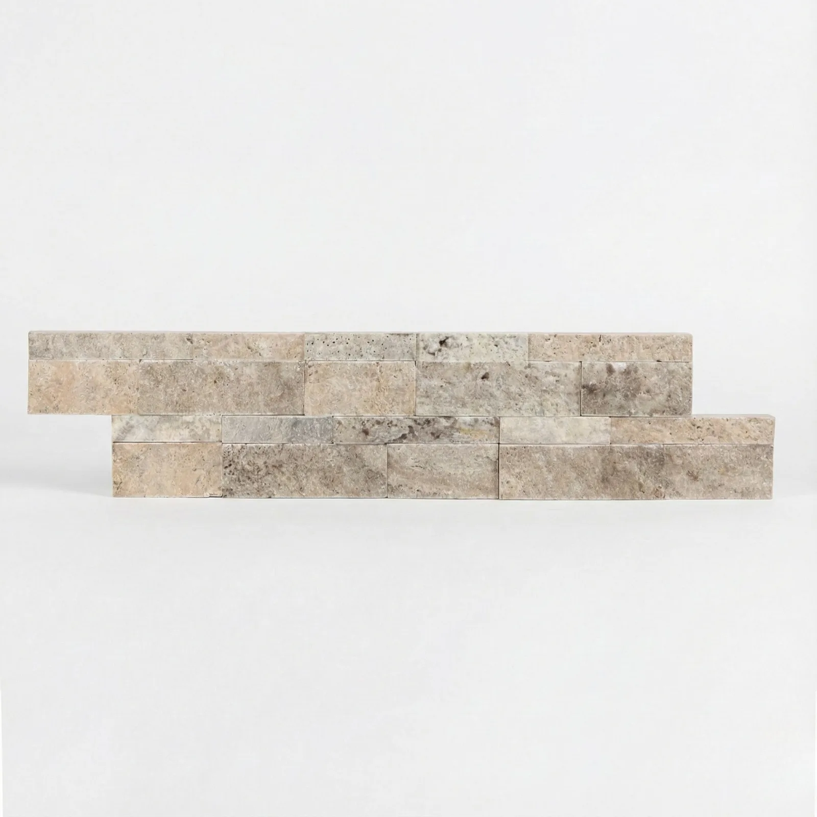Silver travertine corner piece seen at an angle, the broken faces showing the grey and buff layering through the stone.