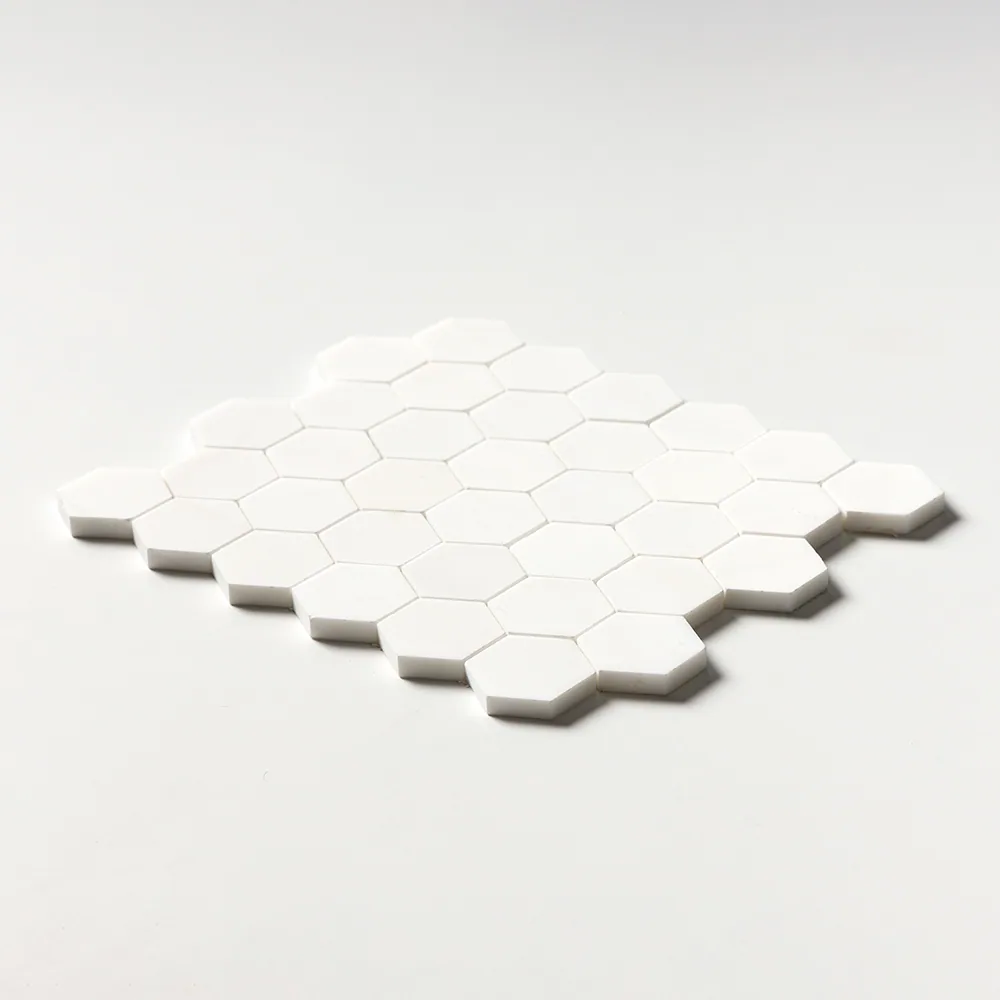 Two-inch hexagons of polished Snow White marble, uniformly bright white, the sheet tilted low against a white ground.