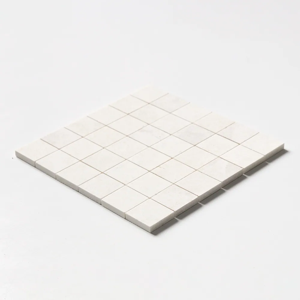 Vanilla marble mosaic of two-inch squares in a soft off-white, matt honed, the sheet seen at a shallow angle.