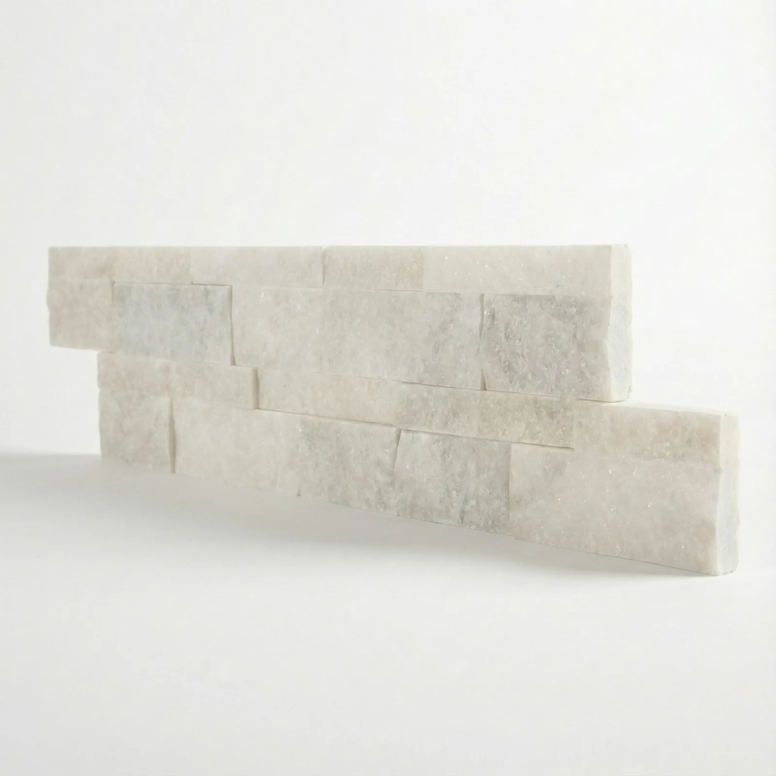 Two courses of white marble ledger panel on a pale studio ground, the split faces catching the light along their top edges.