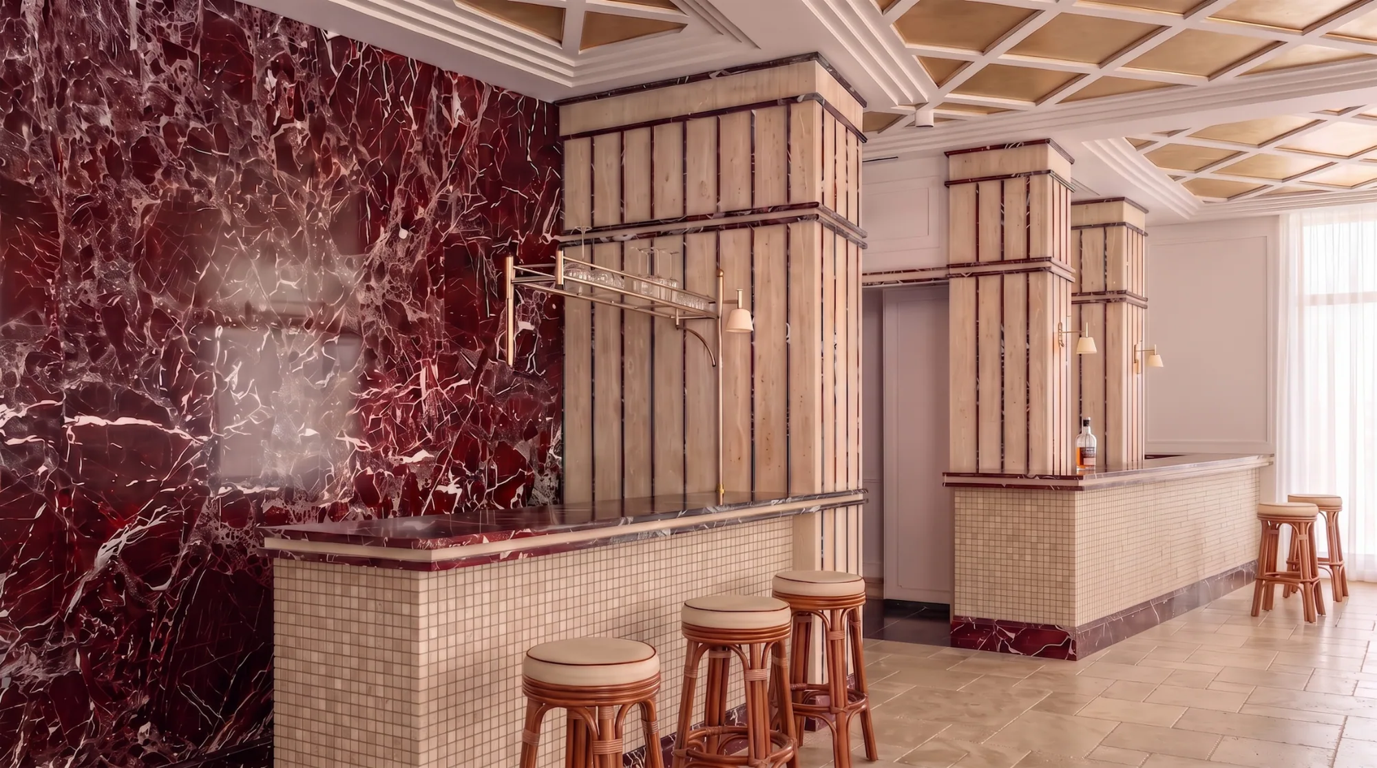 A bar interior: a deep red Rosso Levanto marble wall and counter slab, a cream square-tiled mosaic field running the length of the counter front, timber-clad columns above, and a pale travertine tiled floor.